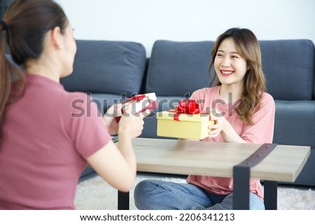 young woman giving gift box to her friend for birthday on a table