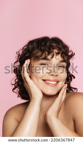 Skin care company campaign. Vertical of curly smiling girl, touches nourished, clear glowing skin without blemishes, has hydrated body after shower, pink background. Royalty-Free Stock Photo #2206367847