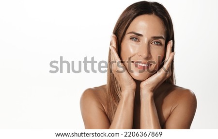 Anti-aging skin lifting beauty. Smiling adult woman in her mid 40s, using hyaluronic acid skin care treatment, smooth nourished face, standing over white background.