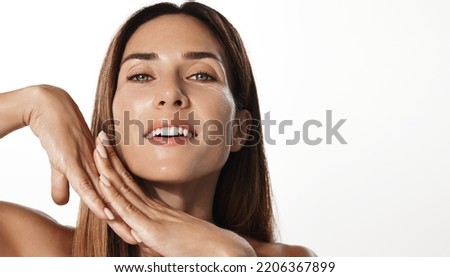 Beauty and skin care. Smiling woman 30 years old with glowing, nourished face, using anti-aging facial treatment, skincare cosmetic product, white background. Royalty-Free Stock Photo #2206367899