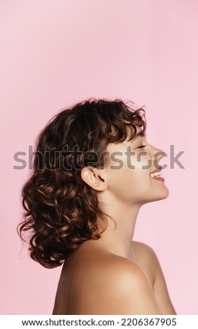 Profile photo of young female model, curly hair, closed eyes, laughing, advertising of skin care treatment, cosmetic and spa product on pink background. Royalty-Free Stock Photo #2206367905
