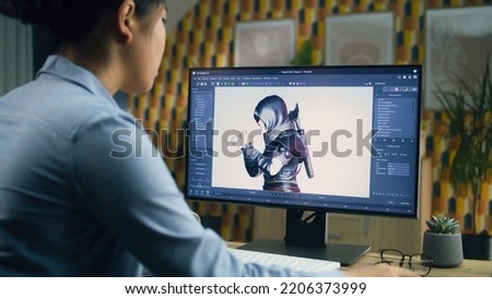 Female 3D designer creating and drawing character for video game using computer while sitting at the table at home office and doing distant work. 3D modeling