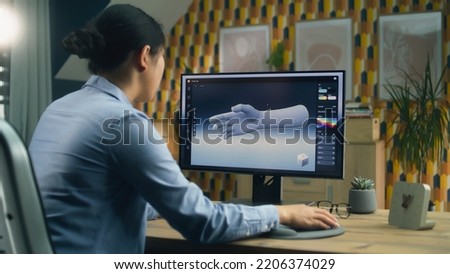 Woman sitting at the table at home office and making 3D prototype of human hand in professional program for 3D modeling using modern computer