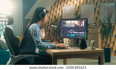 Asian woman sitting at the desk in headphones at home office and editing video for blog in professional program on computer. Freelance