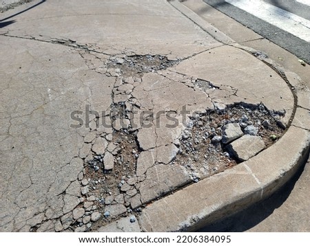 The corner of a sidewalk that is chipped and has lots of holes. Royalty-Free Stock Photo #2206384095