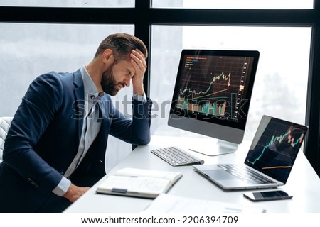 Upset stressed worried caucasian male stock investor, broker, financial expert, sit at work desk in front of computer with charts, nervous of fall cryptocurrency coin, closed eyes, disappointment Royalty-Free Stock Photo #2206394709