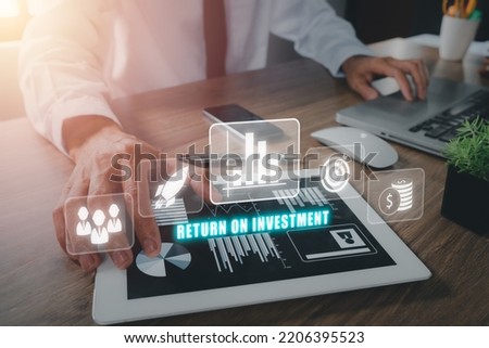 ROI, Return on investment business and technology concept, Person hand using laptop and digital tablet with ROI icon on VR screen. Royalty-Free Stock Photo #2206395523