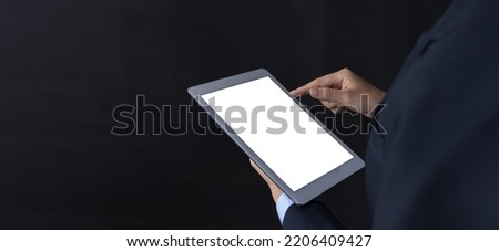Close up of business woman standing and holding tablet blank white screen on black background