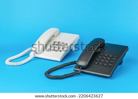 Light and dark telephones on a blue background. The concept of telephone communication. Flat lay.
