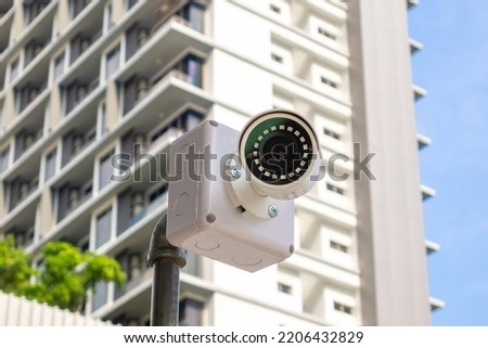 Security surveillance camera in front of high-rise condominium. CCTV camera home security system Royalty-Free Stock Photo #2206432829