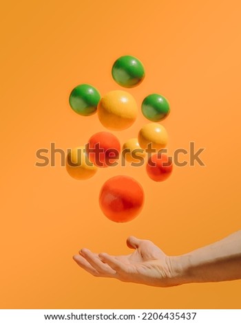 halloween magic wit hand and colorful flying ball on bright orange background, minimal creative composition.
