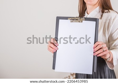 Woman holding clipboard with a blank sheet of paper. Blank paper poster in female hands. Blank template for graphic designers portfolios. To do plans in business, blogging, educations