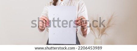 Woman holding a blank sheet of paper with check marks. Blank paper poster in female hands. Blank template for graphic designers portfolios. To do plans in business, blogging, educations