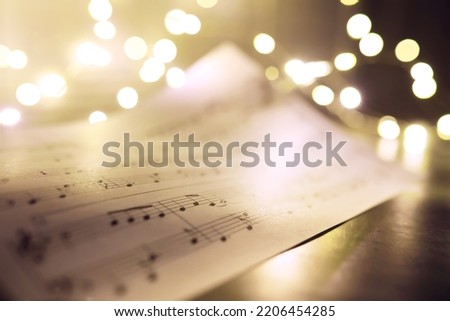 Old sheet with Christmas music notes as background, bokeh effect
