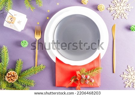 top view of the festive empty plate on the New Year's or Christmas table with a spruce branch, a lantern and confetti. A blank layout for your food