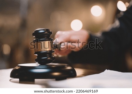 The gavel blow of a judge or decision-maker to authority about business, justice, or the law for a court proceeding. A picture of a hand hitting a hammer for finalizing the decision in courtroom.