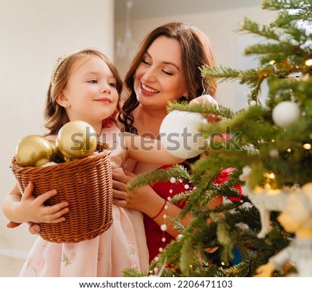 mom and little daughter with toy basket for the Christmas tree. the tradition of decorating the house for the holiday. happy childhood. children's belief in a miracle. the tradition of making gifts. 