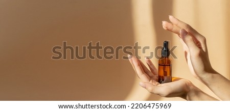 Concept of mockup. Glass bottle with dropper lid with collagen moisturizing hyaluronic serum in morning sun. Amber-colored container with cosmetic product on beige background. Banner, copy space Royalty-Free Stock Photo #2206475969
