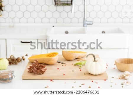 a butternut pumpkin in modern white kitchen. Making pumpkin soup at home. Autumn recipe. Beautiful food photo. High quality photo