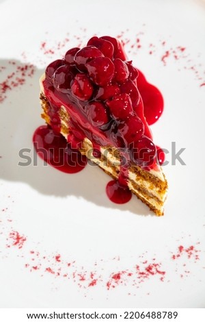 Slice of cake with cherries and cherry jam in a plate on the table