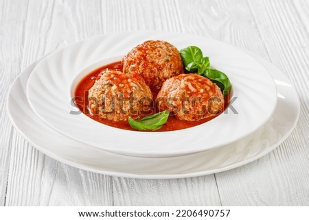 Italian Porcupine Balls, ground beef and rice meatballs in tomato sauce with basil leaves in white bowl, horizontal view from above