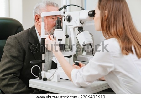 ophthalmologist examination of elderly man with slit lamp. microscope and focused light source. device for high-precision examination of eye to determine condition of lens, cornea. medical equipment.