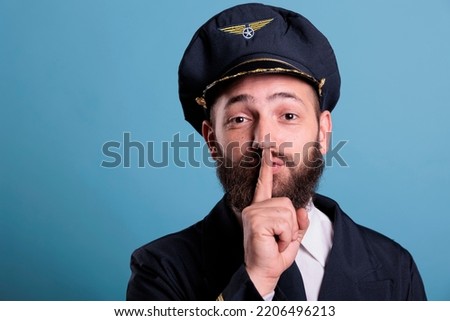 Airplane pilot showing silent gesture, looking at camera with forefinger on lips. Aviation academy plane captain front view, airforce aviator keeping secret, quiet, silence sign