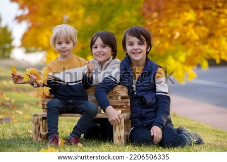 Happy family, mother with children, having their autumn pictures taken in the park, children playing
