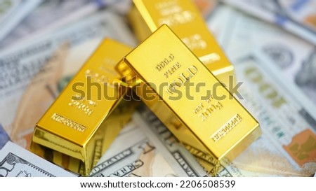 Gold bars on background of US dollars banknotes. Future gold trading and online asset trading or buying gold bars for investment Royalty-Free Stock Photo #2206508539
