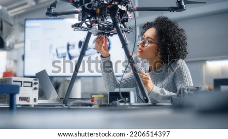 Concentrated Black Female Engineer Writing Code. Developing Software for Modern Drone Control in the Research Center Laboratory. Technological Breakthrough in Flight Industries Concept. Royalty-Free Stock Photo #2206514397