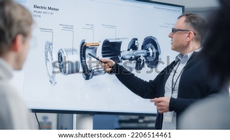 Chief Engineer Points at Television Screen and Talks About Green Energy, Electric Engine Future Possibilities. Engineering and Sustainable Solutions and Higher Education Concept. Royalty-Free Stock Photo #2206514461