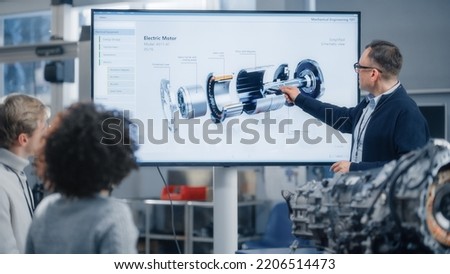 Professor Lectures Diverse Group of Multi Ethnic Students and Pointing at Model of Turbine Engine on Big Television Screen in University. Engineering and Green Electric Energy Concept.