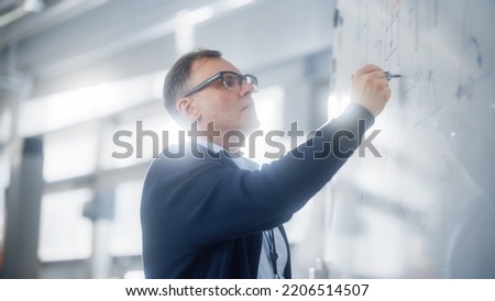 Teacher Talks to Students and Use Chalkboard During University Lecture in Classroom. Smart Caucasian Man Draws Formulas and Schemes on Seminar. Genius Solves Problems Concept. Royalty-Free Stock Photo #2206514507