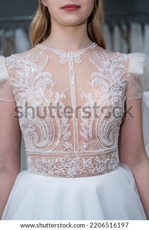 Happy woman trying on elegant wedding dress in a wedding salon, dreaming bride
