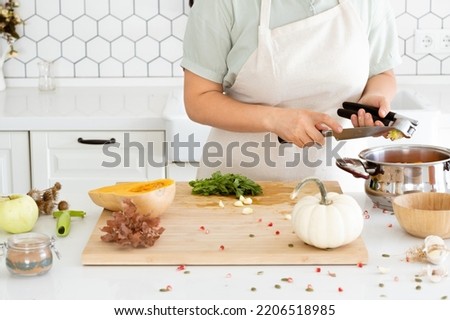 Woman hands cleaning a garlic press in modern white kitchen. Garlic-pressed. Homemade autumn pumpkin soup recipe. High quality photo