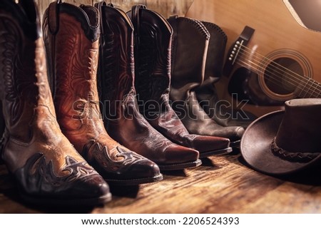 Country music festival live concert concept with acoustic guitar, cowboy hat and three pairs of boots background