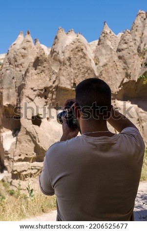 Unrecognizable young male tourist with his camera taking pictures of the fairy chimneys in Cappadocia, Turkey.