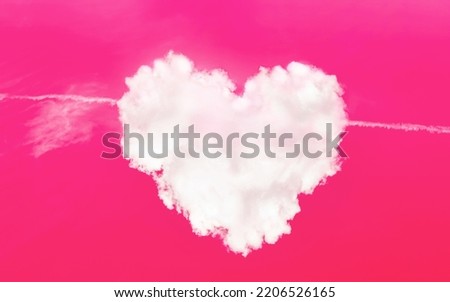 Heart shaped cloud in a pink sky with plane cupid arrow. Love symbol. Cloudscape. Valentine day card. Abstract art. Magic sign. Romantic relationship. Healthy cardio system. Heart muscle care concept.