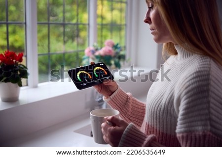 Worried Woman Looking At Smart Meter In Kitchen At Home During Cost Of Living Energy Crisis Royalty-Free Stock Photo #2206535649