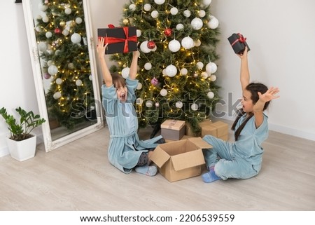 Two little girls open Christmas present under the Christmas tree