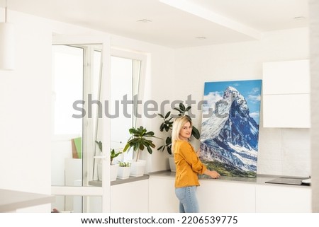 Woman hanging a photo canvas on a wall.