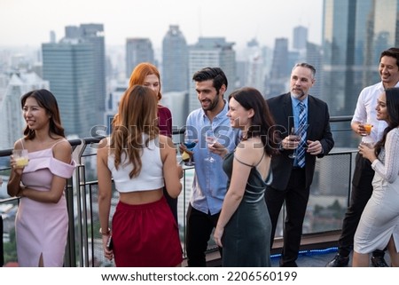 Photo of a group of businessmen and businesswomen mingle with each other drinking wine and champagne on a rooftop bar celebrating the successful of company latest deal and hit target goal of the year