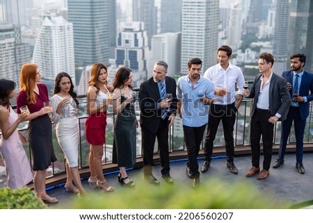 Photo of a group of businessmen and businesswomen mingle with each other drinking wine and champagne on a rooftop bar celebrating the successful of company latest deal and hit target goal of the year Royalty-Free Stock Photo #2206560207