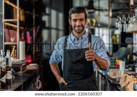 Photo of a handsome bartender doing thumb up pose behind the bar in a sky lounge bar in Bangkok Royalty-Free Stock Photo #2206560307