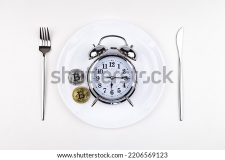 Top view alarm clock on a white plate with a knife and fork on a white background. Intermittent fasting, ketogenic diet, weight loss, meal plan and healthy eating concept
