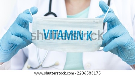 The doctor holds a protective face mask with the word vitamin k. Medical concept.