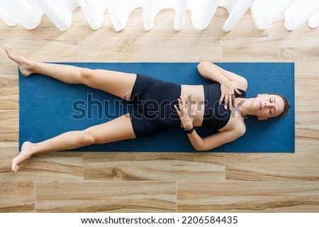 Young woman relaxing in shavasana or corpse yoga pose after her morning fitness routine. Royalty-Free Stock Photo #2206584435