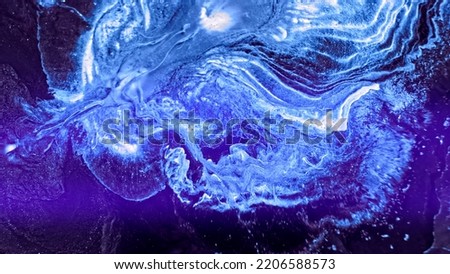 Bright blue neon paint spreads. Abstract colorful blue glowing liquid explosion over dark surface. Action particles on dark area background. Mix ink art blast. Blue flowing paint