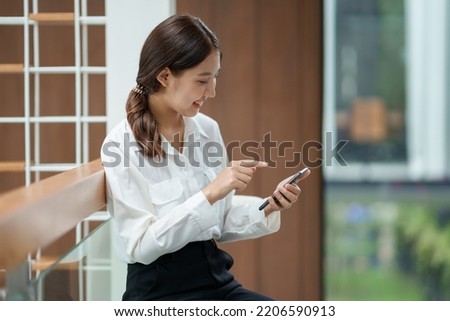 Attractive young Asian woman using mobile phone in the cafe. 