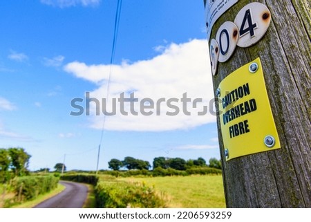 Sign on a wooden telephone pole warning people that the pole is carrying fibre optic cable. Royalty-Free Stock Photo #2206593259